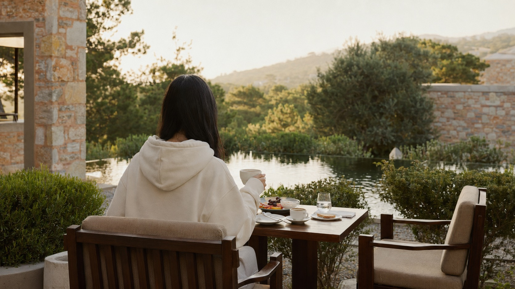 A woman wearing the Hoodie Reset beside a calm pool